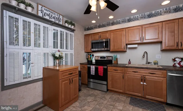 a kitchen with stainless steel appliances granite countertop a stove top oven a sink dishwasher a dining table and chairs with wooden floor