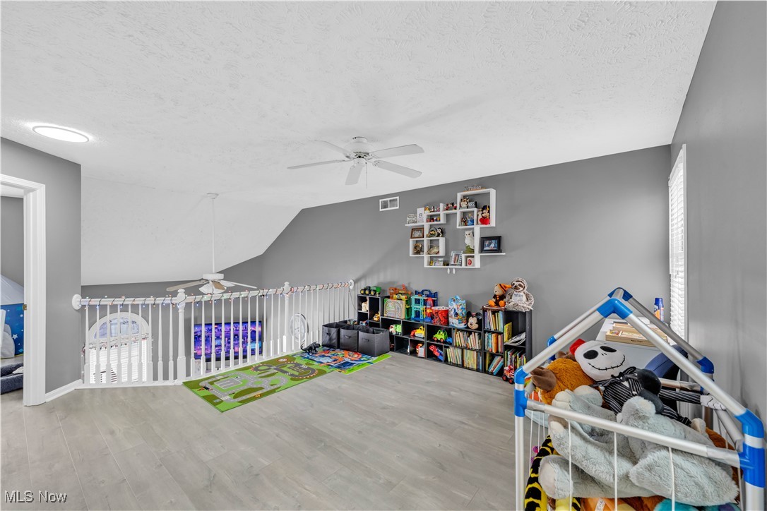1033 Parsons Road Grafton, OH 44044 - Photo 10 of 25 Playroom featuring a ceiling fan, light wood-style flooring, a textured ceiling, and lofted ceiling