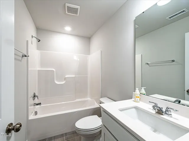 a bathroom with a granite countertop bathtub shower sink vanity mirror and toilet