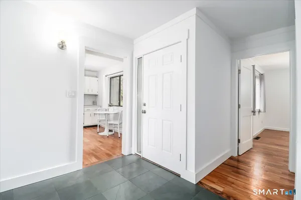 a view of a hallway with wooden floor and a bathroom