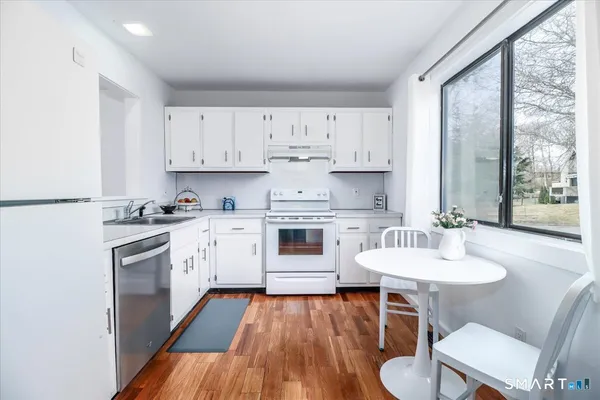 a kitchen with stainless steel appliances white cabinets a sink a stove a refrigerator with a dining table and chairs