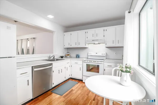 a kitchen with granite countertop white cabinets and white appliances
