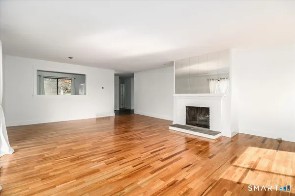 a view of empty room with wooden floor and fireplace
