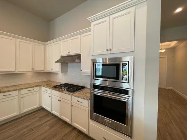 a kitchen with kitchen island granite countertop a refrigerator and a stove top oven