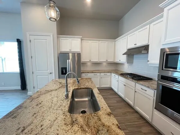 a kitchen with kitchen island granite countertop a sink and refrigerator