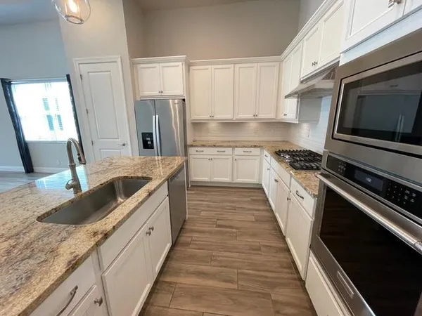 a kitchen with stainless steel appliances granite countertop a stove a sink dishwasher and a refrigerator