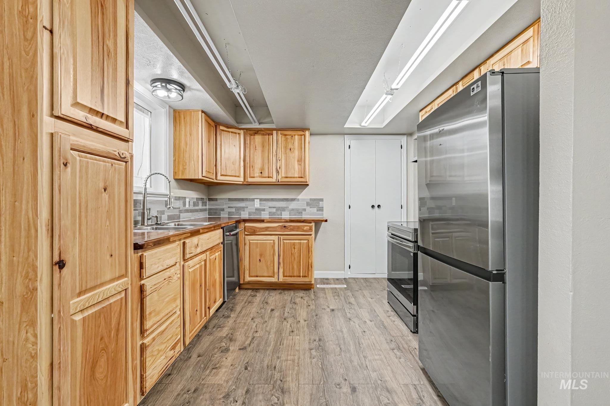 1023 State Street Weiser, ID 83672 - Photo 7 of 25 Kitchen featuring extensive natural wood cabinetry, wood-finish flooring, stainless steel appliances, a tile backsplash, and recessed lighting