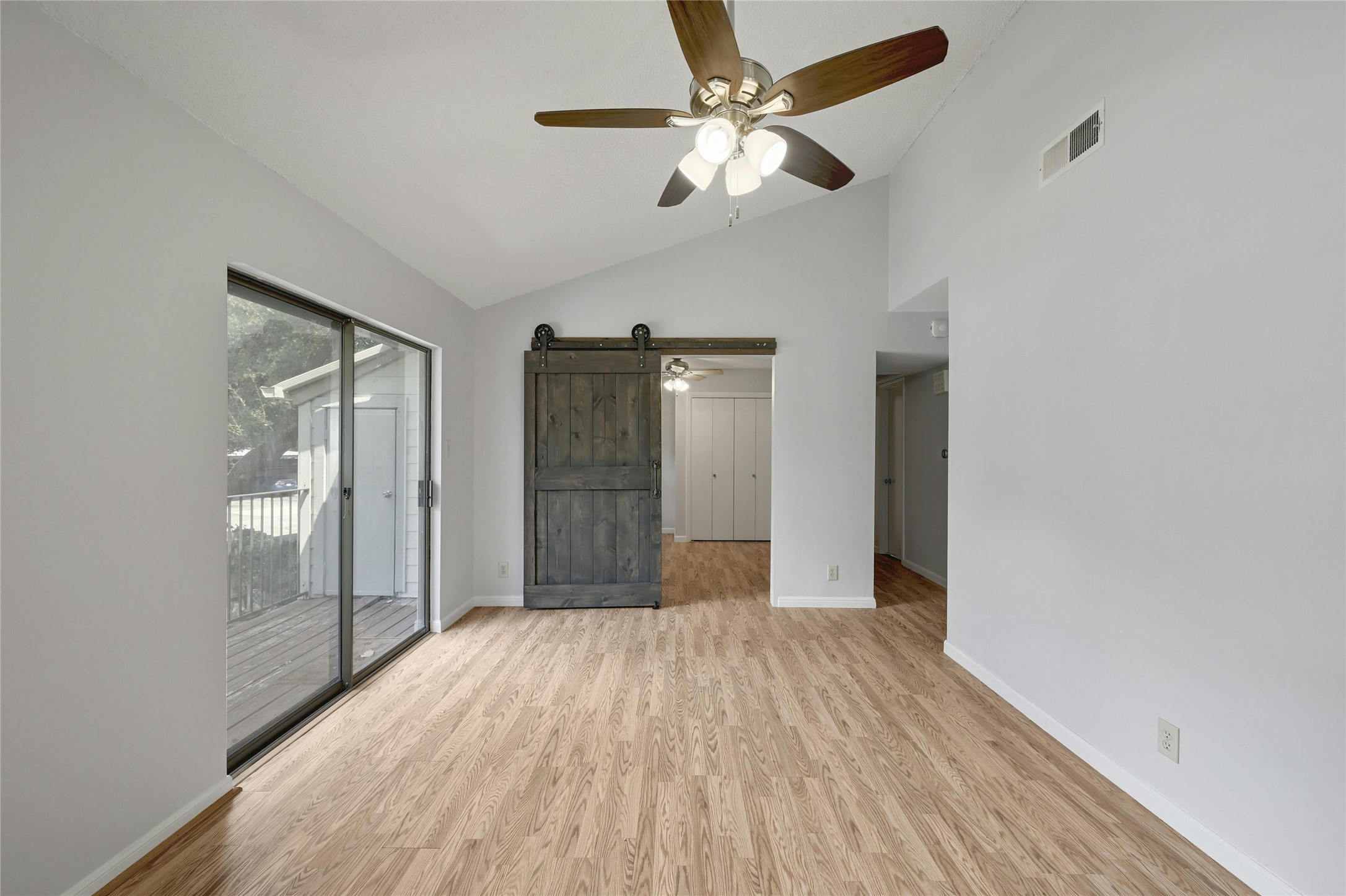 9226 Jollyville Road, Unit 221 Austin, TX 78759 - Photo 12 of 20 A comfortable living space boasts a sliding barn door and access to a secluded deck, perfect for indoor-outdoor living.