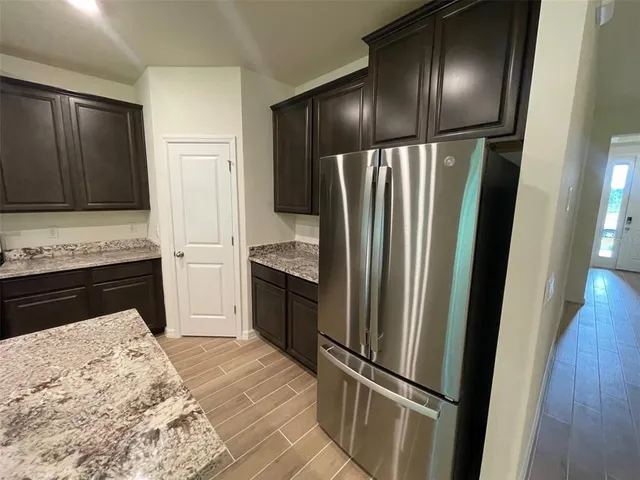 a kitchen with granite countertop stainless steel appliances a refrigerator and a stove top oven