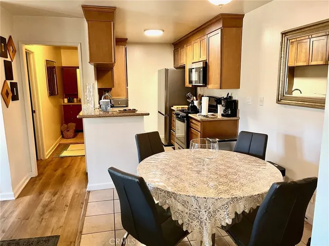 a kitchen with stainless steel appliances kitchen island granite countertop a table chairs and a refrigerator