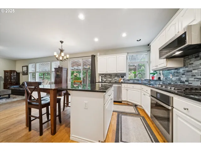 a kitchen with granite countertop a table chairs stove and cabinets