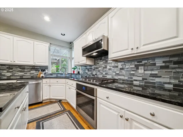 a kitchen with granite countertop a sink stainless steel appliances and cabinets