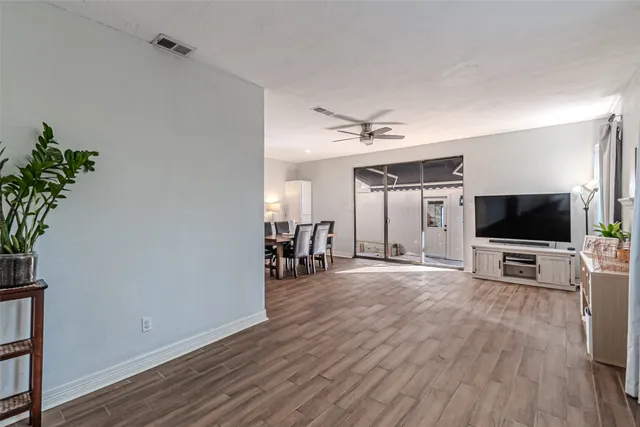 a view of a livingroom with a flat screen tv wooden floor and a ceiling fan