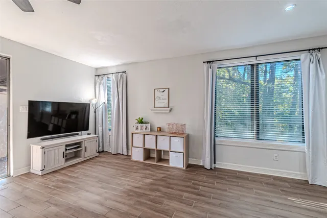 a view of a livingroom with furniture flat screen tv wooden floor and windows