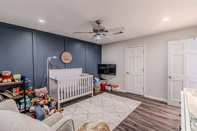 a bedroom with furniture a flat screen tv and a ceiling fan