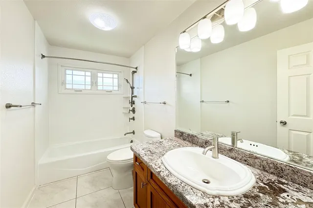 a bathroom with a granite countertop sink a toilet a mirror and shower