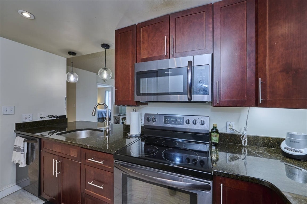 10 Museum Way, Unit 525 Cambridge, MA 02141 - Photo 7 of 22 a kitchen with granite countertop a sink and cabinets