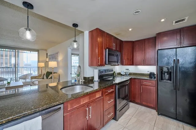 a kitchen with granite countertop stainless steel appliances a sink a stove cabinets counter space and a window
