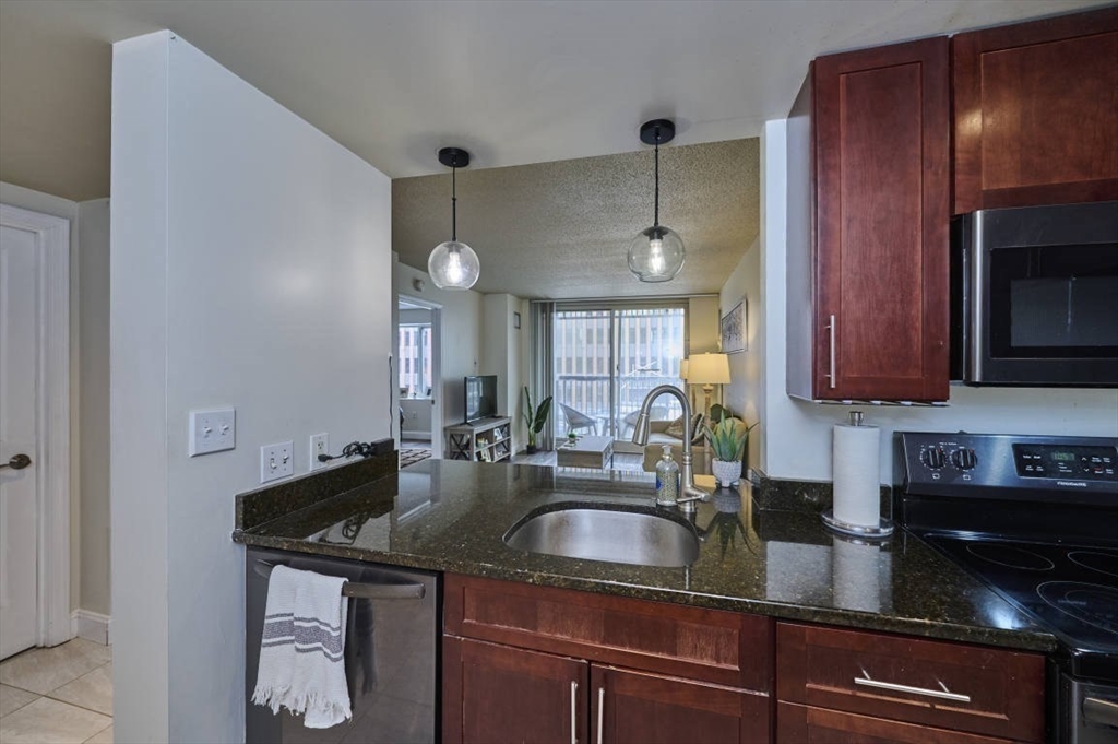 10 Museum Way, Unit 525 Cambridge, MA 02141 - Photo 9 of 22 a kitchen with granite countertop stainless steel appliances a sink a stove cabinets counter space and a window
