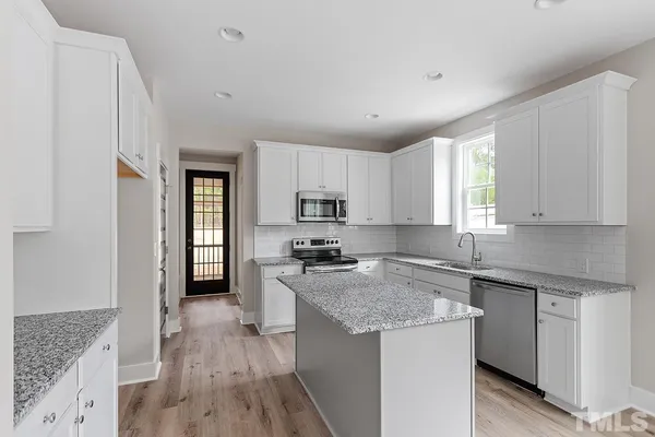 a kitchen with granite countertop a sink stove and refrigerator