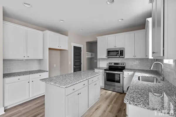 a kitchen with stainless steel appliances granite countertop a sink stove microwave and refrigerator