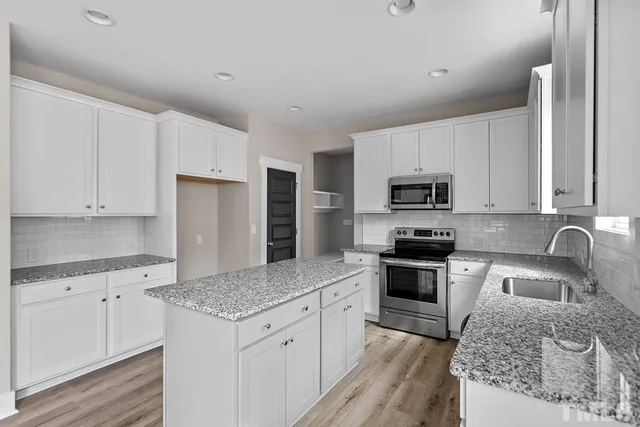 a kitchen with stainless steel appliances granite countertop a sink stove microwave and refrigerator