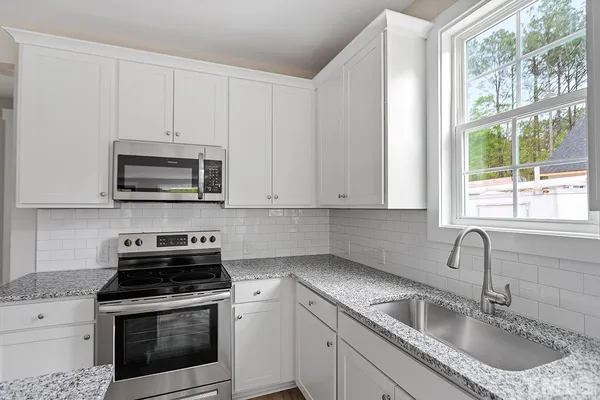 a kitchen with granite countertop white cabinets a sink and a stove