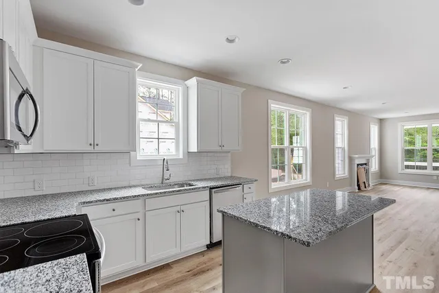a kitchen with granite countertop a sink a stove and cabinets
