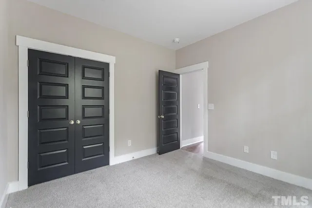 a view of an empty room with closet and a window