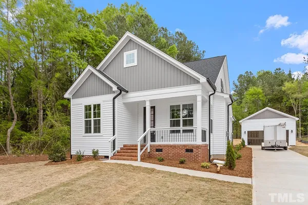a view of house with backyard and trees in the background