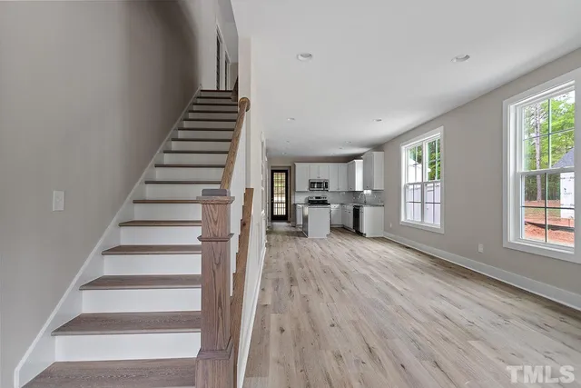 a view of a livingroom with wooden floor and stairs
