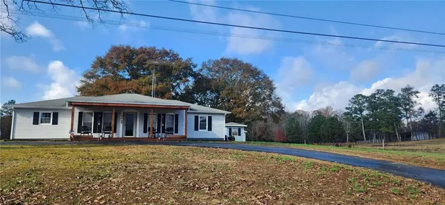 a front view of a house with a garden and trees