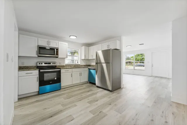 a kitchen with a refrigerator cabinets and wooden floor