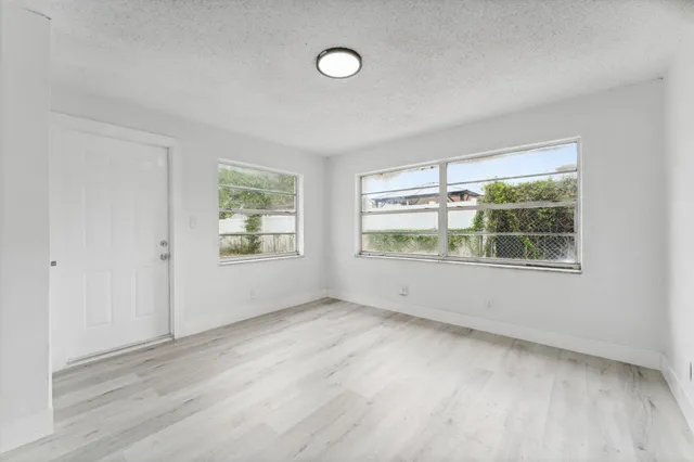 a view of an empty room with a window and wooden floor