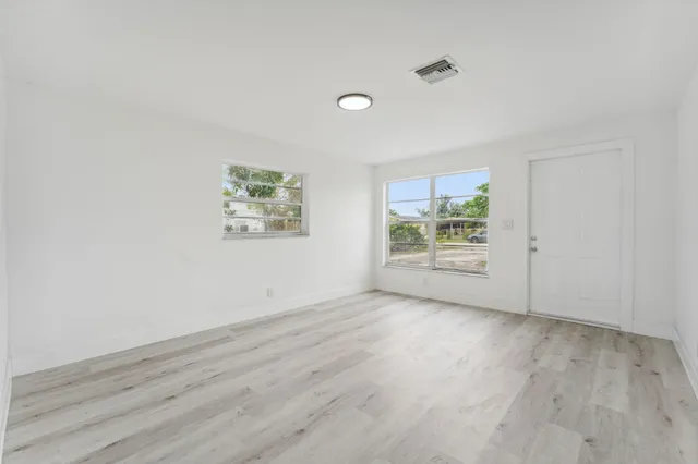 an empty room with wooden floor and windows