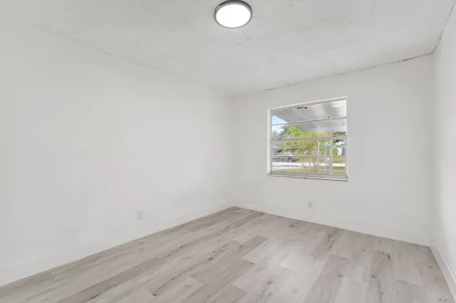 an empty room with wooden floor and window