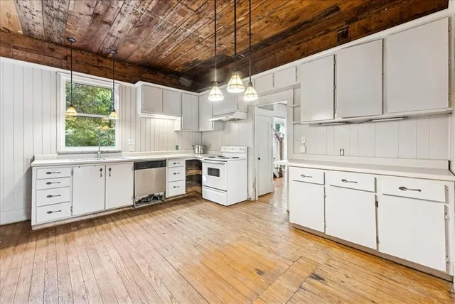 a kitchen with stainless steel appliances white cabinets and wooden floors