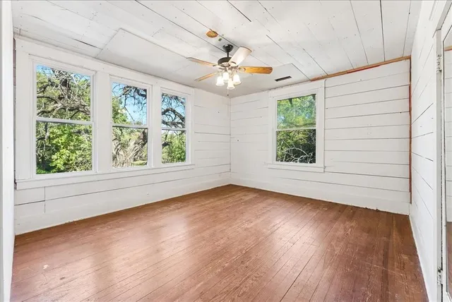an empty room with wooden floor chandelier and windows