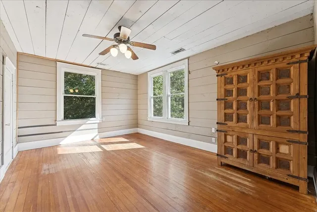 a view of an empty room with wooden floor and a window