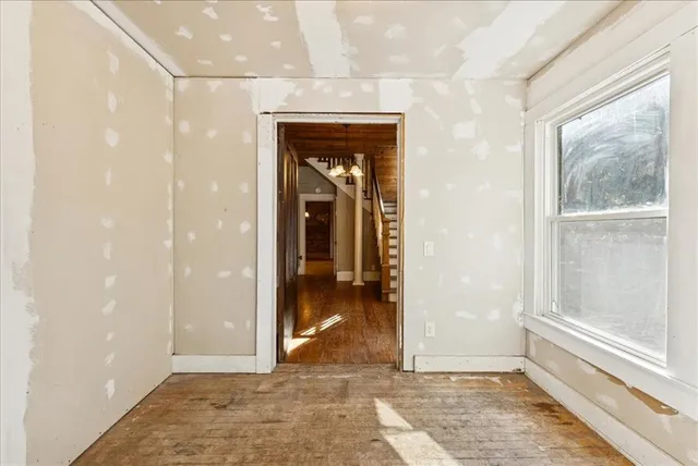 a view of a hallway with wooden floor and a bathroom