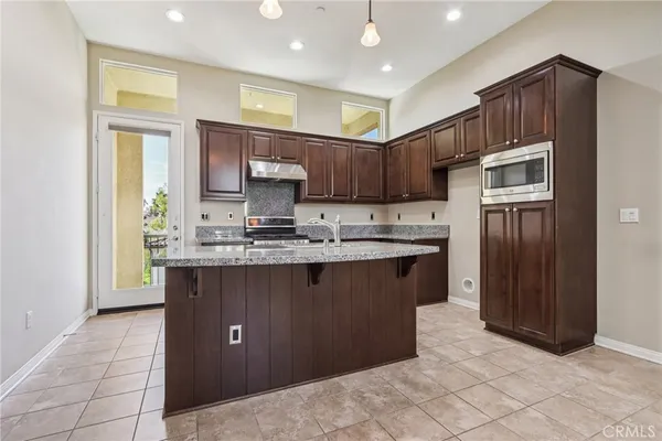 a kitchen with kitchen island granite countertop wooden cabinets a refrigerator and a sink