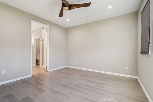 an empty room with wooden floor cabinet and a ceiling fan