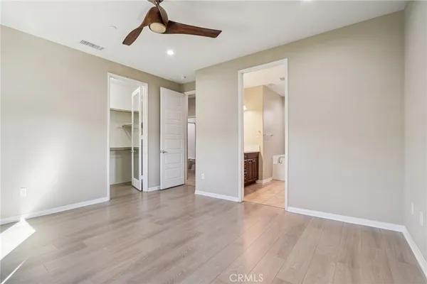 a view of an empty room with wooden floor and a ceiling fan
