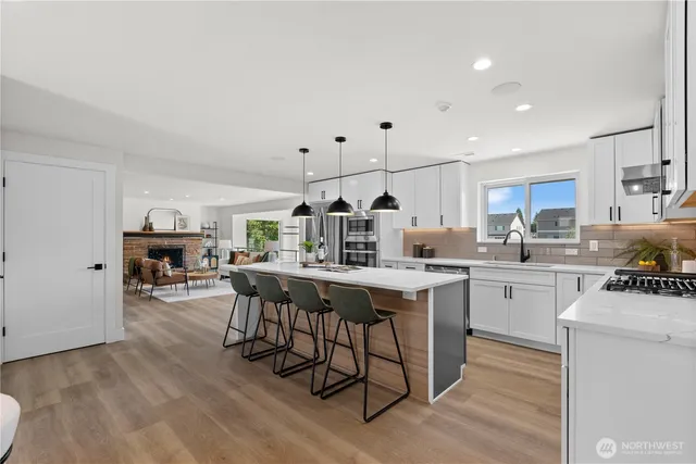 a kitchen with stainless steel appliances kitchen island granite countertop a table chairs sink and cabinets