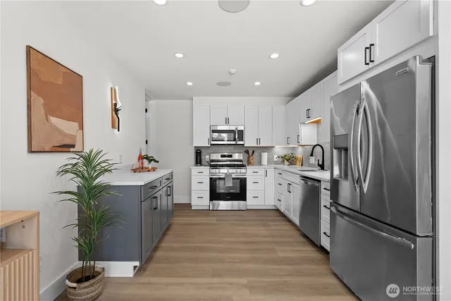 a kitchen with stainless steel appliances a dining table chairs stove and white cabinets