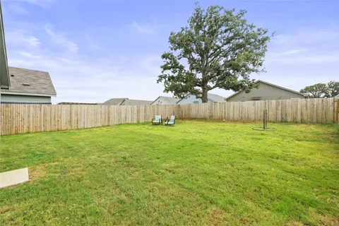 a view of a backyard with large tree and wooden fence