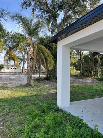 a view of a yard in front of a house with a large tree