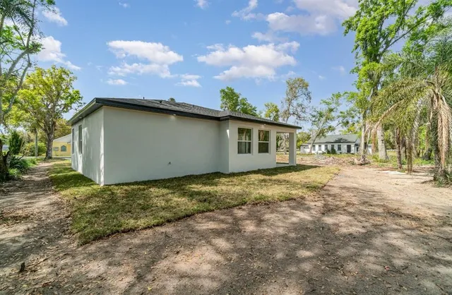 a backyard of a house with large trees and table and chairs