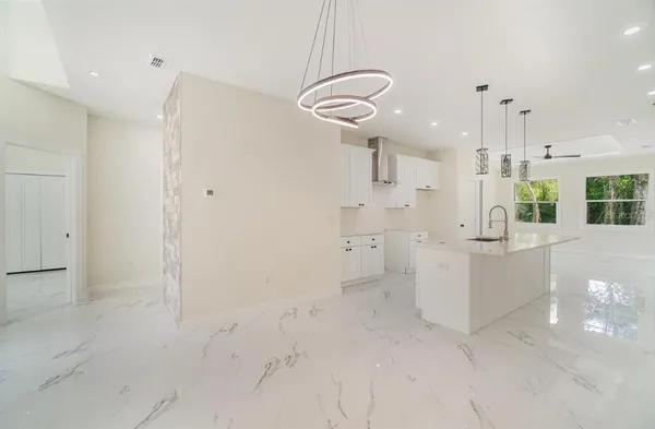 a large white kitchen with a lot of cabinets and refrigerator