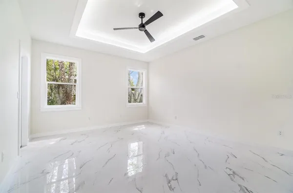 an empty room with windows and fan